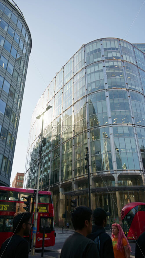 London, England – May 13, 2025: Modern glass skyscrapers of London’s financial district reflecting the blue sky next to historic architecture. Vertical - Starpik Stock