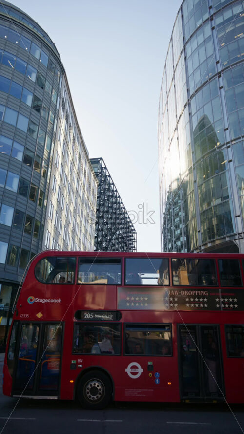 London, England – May 13, 2025: Modern glass skyscrapers of London’s financial district reflecting the blue sky next to historic architecture. Vertical - Starpik Stock
