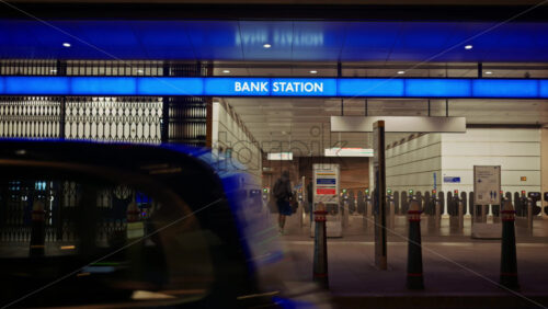 London, England – May 13, 2025: Night scene at the entrance of Bank Station with people entering through ticket gates under a glowing blue sign - Starpik Stock