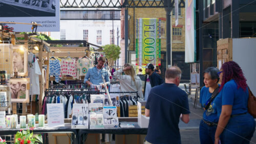 London, England – May 13, 2025: Spitalfields Market with people browsing through racks of vintage clothing and handmade goods - Starpik Stock