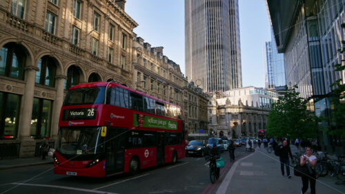 London, England – May 13, 2025: Time lapse of iconic red double-decker buses driving through the heart of the city’s financial district surrounded by historic and modern architecture - Starpik Stock