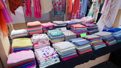 London, England – May 13, 2025: Vibrant cashmere scarves stacked and hanging at a textile vendor’s stall in Spitalfields Market, showcasing patterns and colors. - Starpik Stock