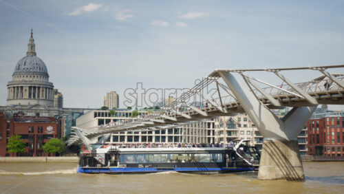 London, England – May 14, 2025: A scenic view of London’s iconic skyline featuring St. Paul’s Cathedral with a tour boat sailing along the River Thames on a sunny day - Starpik Stock