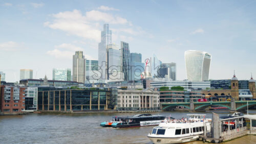 London, England – May 14, 2025: A scenic view of London’s iconic skyline featuring The Shard and Tower Bridge with a tour boat sailing along the River Thames on a sunny day - Starpik Stock