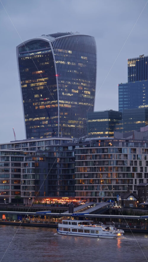 London, England – May 14, 2025: Cityscape view showing the Thames River, modern skyscrapers, including the Walkie Talkie building, and the Tower of London. Vertical - Starpik Stock