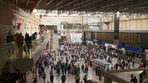 London, England – May 14, 2025: Commuters walking beneath the iconic departure board in the sunlit interior of Waterloo Station - Starpik Stock
