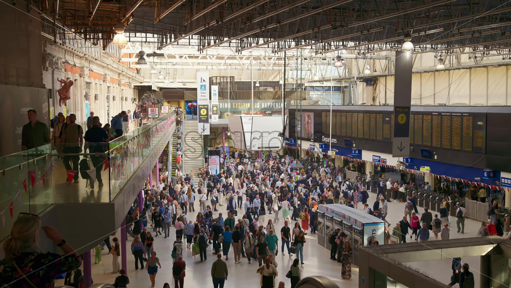 London, England – May 14, 2025: Commuters walking beneath the iconic departure board in the sunlit interior of Waterloo Station - Starpik Stock