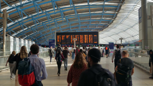 London, England – May 14, 2025: Commuters walking beneath the iconic departure board in the sunlit interior of Waterloo Station - Starpik Stock