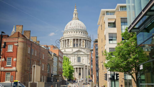 London, England – May 14, 2025: Framed view of St. Paul’s Cathedral dome between two modern brick buildings - Starpik Stock