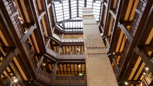 London, England – May 14, 2025: Inside the Liberty department store in London, showcasing its distinctive timbered and iron interior architecture and a tall central pillar with inscriptions - Starpik Stock