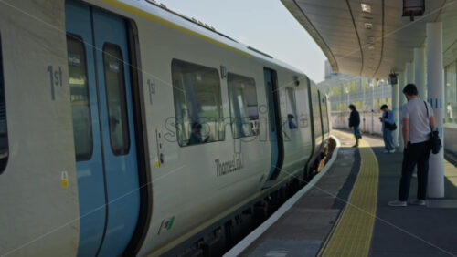 London, England – May 14, 2025: Passengers waiting and boarding at Deptford train station platform in daylight - Starpik Stock
