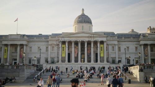 London, England – May 14, 2025: People sitting and moving on the steps of the The National Gallery museum in daylight. Trafalgar Square - Starpik Stock