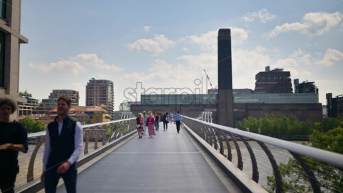 London, England – May 14, 2025: People walking across Millennium Bridge toward the Tate Modern museum - Starpik Stock