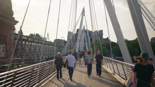 London, England – May 14, 2025: People walking across the Golden Jubilee Bridge over the Thames - Starpik Stock