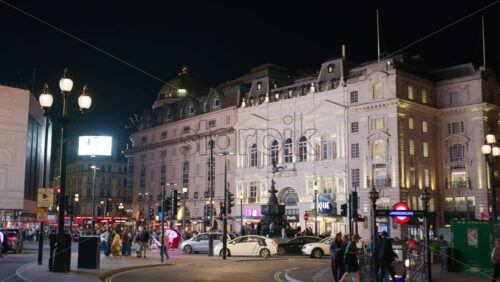 London, England – May 14, 2025: Piccadilly Circus Underground lit up at night with people walking under a vibrant urban glow - Starpik Stock