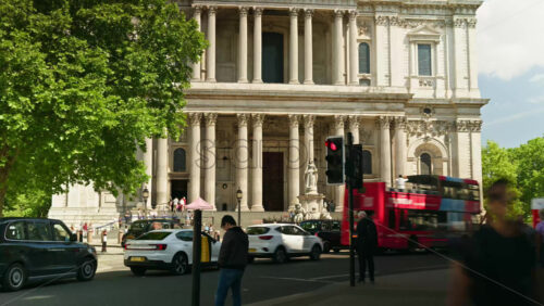 London, England – May 14, 2025: Time lapse of red double-decker buses, people, and cars moving in front of the St. Paul’s Cathedral in daylight - Starpik Stock