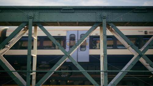 London, England – May 14, 2025: Train crossing a metal bridge with the London Eye in the background - Starpik Stock
