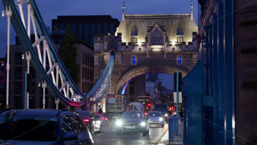 London, England – May 15, 2025: Cars moving on the Tower Bridge at twilight with blue lighting on the arches - Starpik Stock