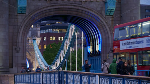 London, England – May 15, 2025: Close up of the Tower Bridge at twilight with blue lighting on the arches and people walking on it - Starpik Stock