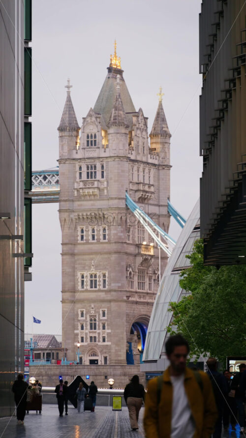 London, England – May 15, 2025: Close up of the Tower Bridge at twilight with blue lighting on the arches and people walking on it. Vertical - Starpik Stock