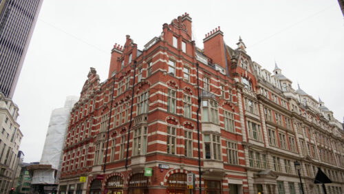 London, England – May 15, 2025: Historic red-brick building on the corner of a busy street - Starpik Stock