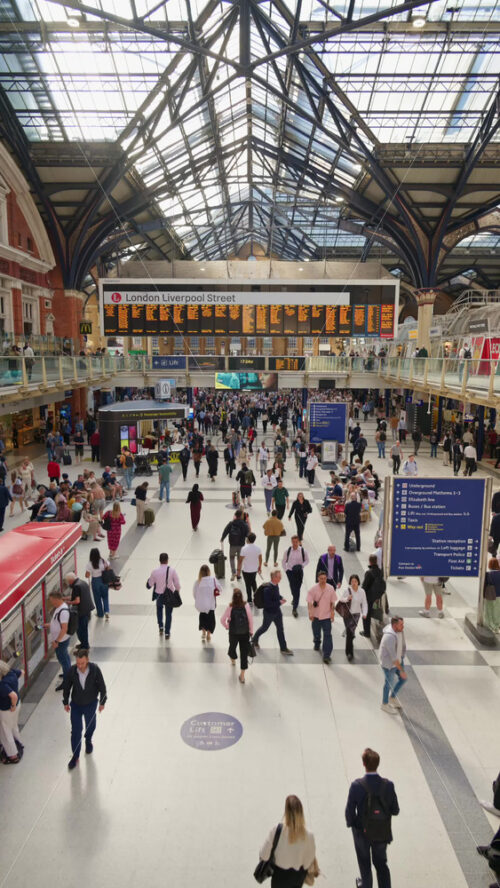 London, England – May 15, 2025: Interior of Liverpool Street busy train station with a high glass ceiling and brick walls filled with commuters. Vertical - Starpik Stock