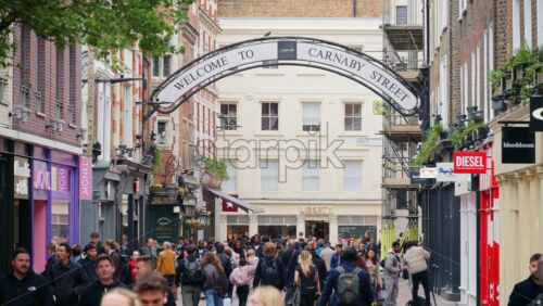 London, England – May 15, 2025: People walking under Carnaby Street sign with many store signs - Starpik Stock