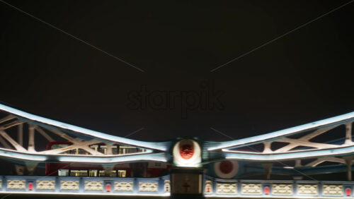 London, England – May 15, 2025: Red double decker moving on the Tower Bridge at night - Starpik Stock
