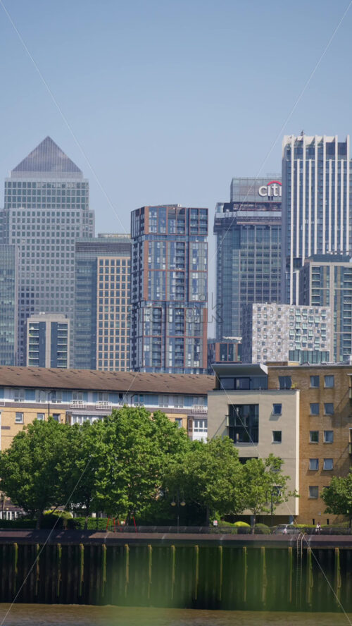 London, England – May 15, 2025: View of a modern glass office Canary Wharf buildings in the skyline of the city. Vertical - Starpik Stock