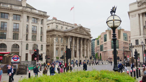 London, England – May 15, 2025: View of people moving in front of the Royal Exchange building with surrounding skyscrapers and monument statues - Starpik Stock