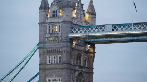 London, England – May 15, 2025:Tower Bridge close-up with some people walking on the bridge and its iconic towers lit up in blue - Starpik Stock