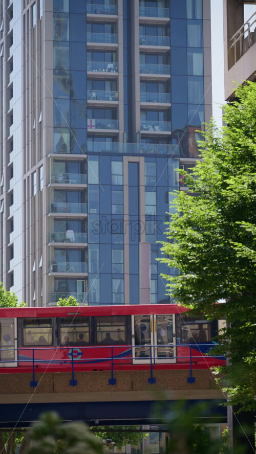 London, England – May 16, 2025: A Docklands Light Railway moving through Canary Wharf. Vertical - Starpik Stock