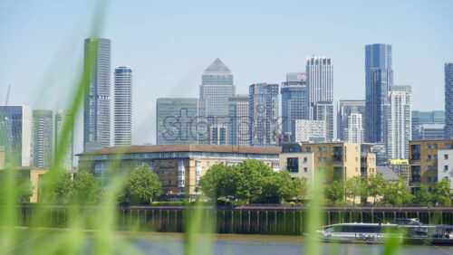 London, England – May 16, 2025: Close up of greenery with the Canary Wharf skyline in the background in daylight - Starpik Stock