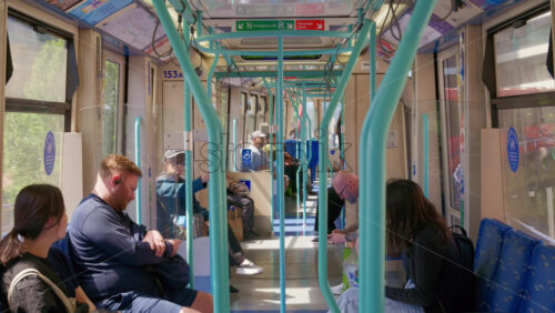 London, England – May 16, 2025: Interior view of a light rail tram or train car during the day with passengers seated on both sides - Starpik Stock