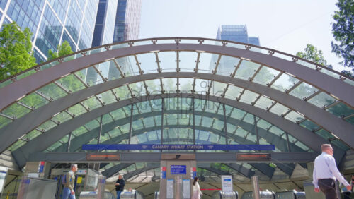London, England – May 16, 2025: Modern architectural view of Canary Wharf Station entrance featuring a glass and steel canopy with office towers in the background - Starpik Stock