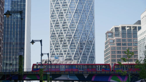 London, England – May 16, 2025: Red Docklands Light Railway train passing by in Canary Wharf - Starpik Stock