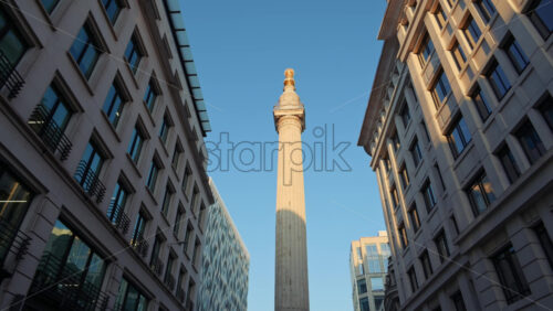 Low-angle view of The Monument to the Great Fire of London with The Shard in the background against a clear sky - Starpik Stock