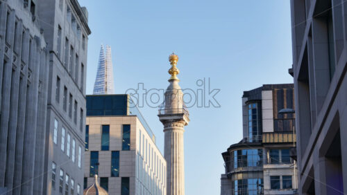 Low-angle view of The Monument to the Great Fire of London with The Shard in the background against a clear sky - Starpik Stock