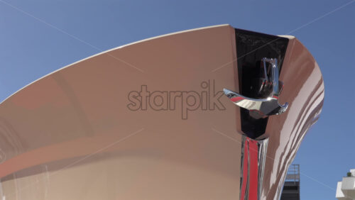 Low angle view of a glossy yacht bow showcasing polished chrome anchor hardware against a clear blue sky - Starpik Stock