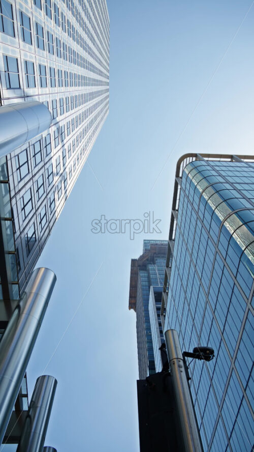 Low angle view of a modern glass One Canada Square office buildings in Canary Wharf, London, England in the evening. Vertical - Starpik Stock