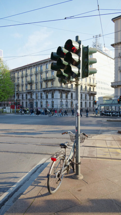Milan, Italy – March 20, 2025: A brown and green bike parked on the street with people and cars moving on the background. Vertical - Starpik Stock