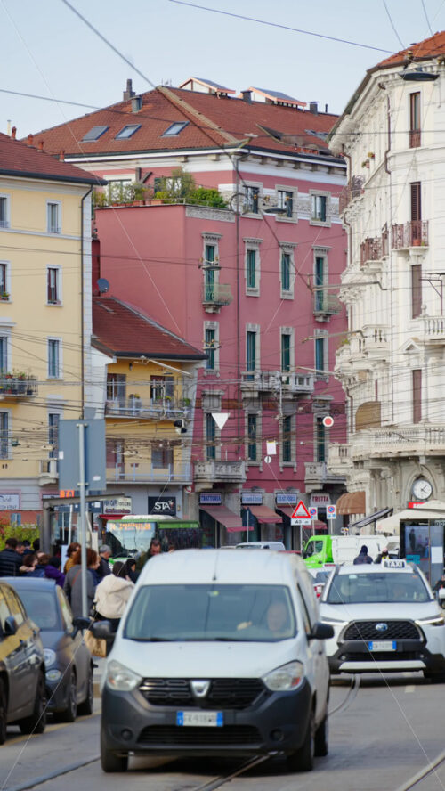Milan, Italy – March 20, 2025: People, cars and public transportation moving on the streets of the city in daylight. Vertical - Starpik Stock