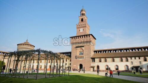 Milan, Italy – March 20, 2025: People walking at the Sforzesco Castle, near the Filarete Tower in daylight - Starpik Stock