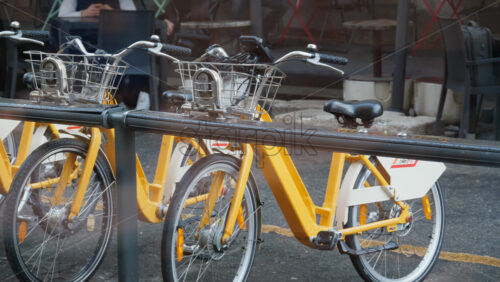 Milan, Italy – March 20, 2025: People walking by yellow, parked bicycles on the street - Starpik Stock
