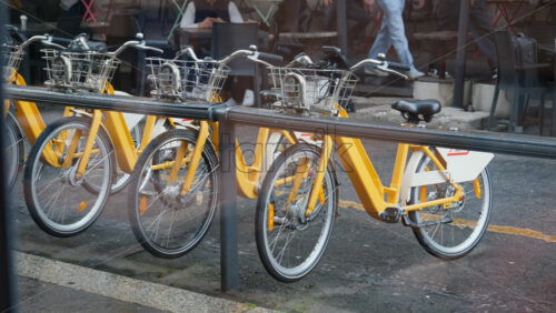 Milan, Italy – March 20, 2025: People walking by yellow, parked bicycles on the street - Starpik Stock