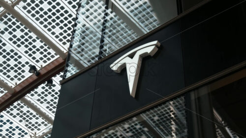 Milan, Italy – March 21, 2025: Big, white Tesla logo on a glass wall at the Showroom - Starpik Stock