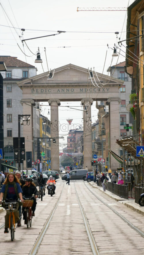 Milan, Italy – March 21, 2025: People and cras moving near the Medieval Ticinese Gate in daylight. Vertical - Starpik Stock