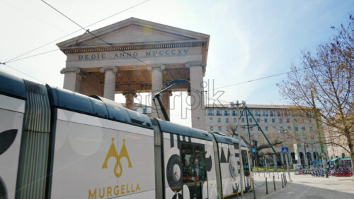 Milan, Italy – March 21, 2025: Tram passing by the Medieval Ticinese Gate in daylight - Starpik Stock