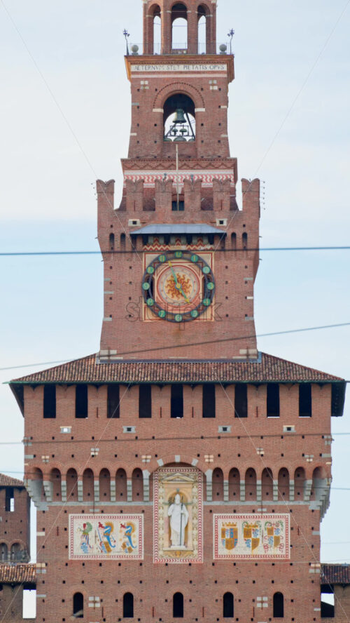 Milan, Italy – March 21, 2025: View of people walking by the Filarete Tower on the blue sky background. Vertical - Starpik Stock