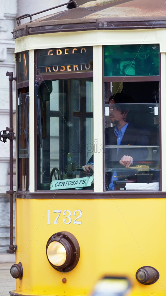 Milan, Italy – March 21, 2025: Yellow tram moving on the streets of the city in daylight. Vertical - Starpik Stock